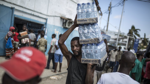 A man carries packets of bottled drinking water from a distribution centre in Beira, Mozambique, on Friday, March 29.