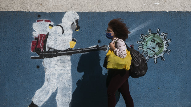A woman walks past a mural in Rio de Janeiro depicting Brazil's President Jair Bolsonaro as a coronavirus.