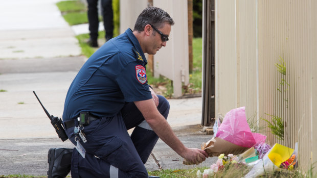 A paramedic lays flowers at the scene.