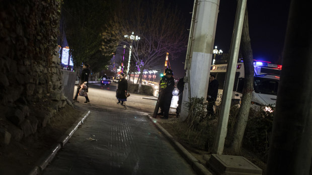 Police officers exit a police vehicle at night in Kashgar.