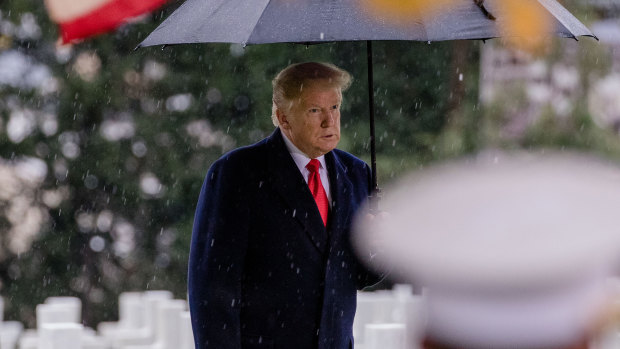 Brooding: US President Donald Trump shelters under an umbrella during a commemoration at the Suresnes American Cemetery in Paris on Sunday.