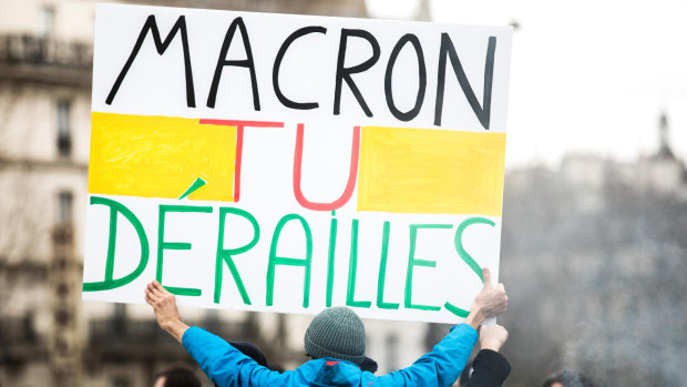 "Macron, you're off the rails": A protester holds up a banner during a protest  on Tuesday.