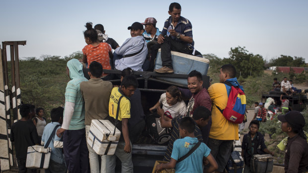 Vendors approach Venezuelan migrants as they ride in a pickup truck in the border town of Paraguachon, La Guajira, Colombia, in  August.
