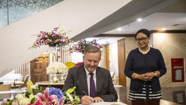 Anthony Albanese signs a guest book as Indonesian Foreign Minister Retno Marsudi looks on at the Indonesia foreign ministry office in Jakarta.