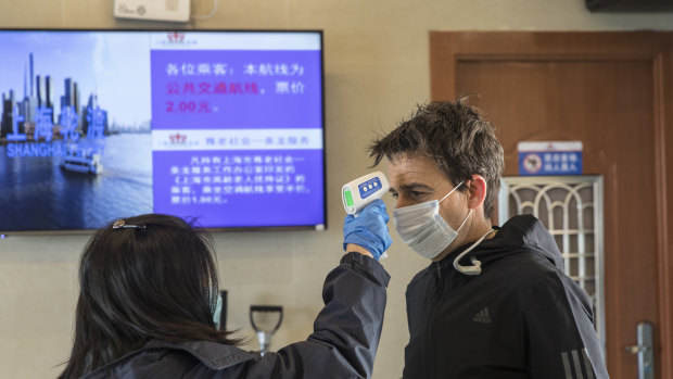 A transit worker takes the temperature of a passenger during a screening at a passenger ferry terminal in Shanghai, China. 