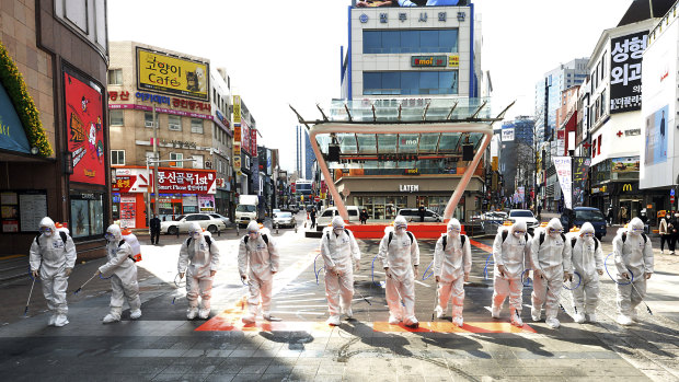 South Korean army soldiers wearing protective suits spray disinfectant to prevent the spread of the COVID-19 in Daegu.