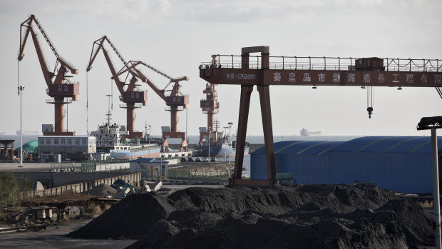 Piles of coal sit near port facilities as gantry cranes stand in the background at the Qinhuangdao Port.