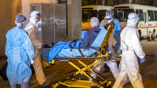 Medical workers in protective gear transport a patient believed to be a confirmed case of the coronavirus.