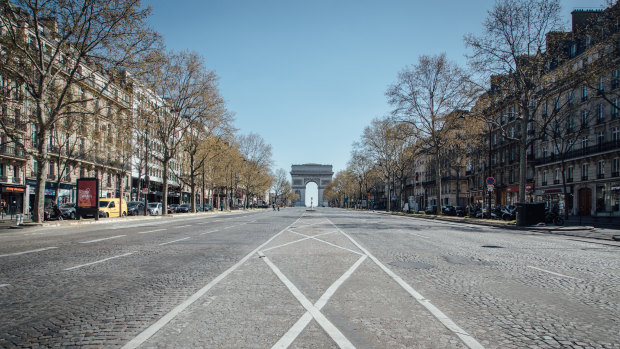 The Arc de Triomphe monument stands at the end of the empty Avenue de la Grande Armee in Paris, France.