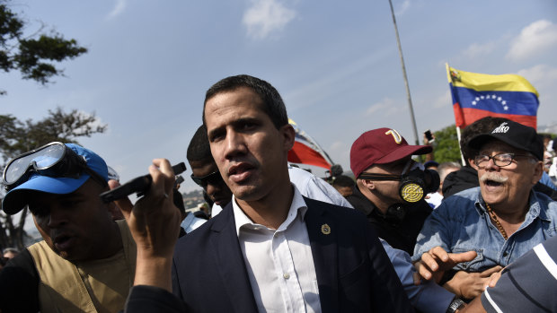Juan Guaido, recognised by many Western nations as the interim president of Venezuela, centre, walks through a crowd after calling for people to rise against Maduro. 