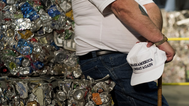 An attendee sits on a stack of crushed aluminium cans before the start of a campaign event with Donald Trump.