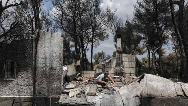 An owner searches through the debris of her house in Mati, Greece, on Wednesday.