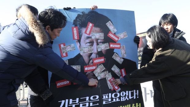 South Korean protesters attach fake Japanese banknotes on an image of Japanese Prime Minister Shinzo Abe during a rally denouncing a bill on Japan's wartime forced labour, which is being pushed by South Korea's parliamentary speaker in front of the National Assembly in Seoul.