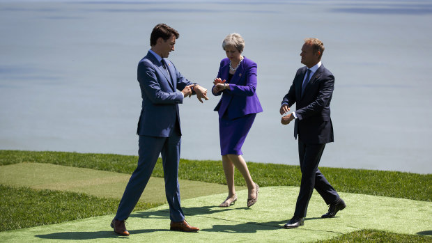 Time to unite: Justin Trudeau, Theresa May, and Donald Tusk check their watches at the G7 in La Malbaie, Quebec.