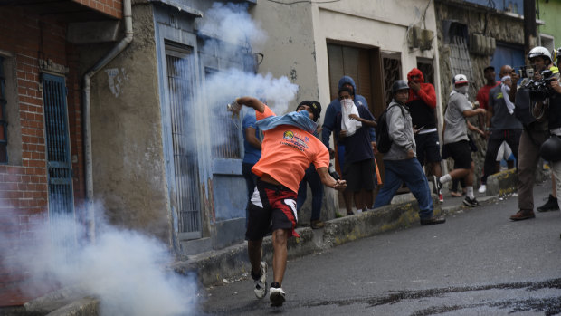 A demonstrator throws back a tear gas canister during a protest in the Cotiza neighbourhood of Caracas on Monday.