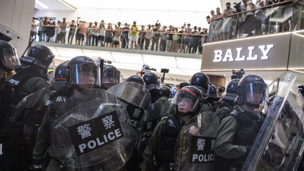 Riot police stand off against demonstrators in front of a Bally store inside New Town Plaza shopping mall.