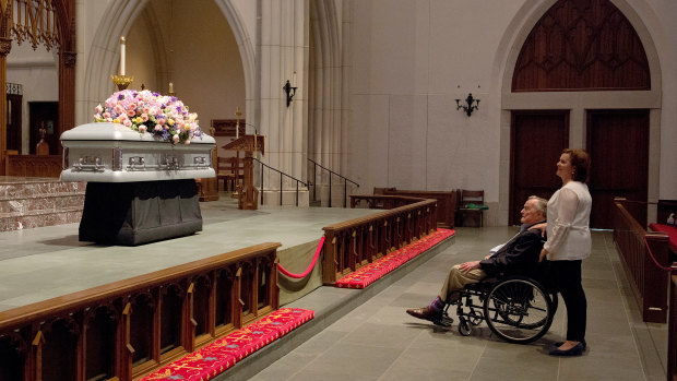 Former president George H.W. Bush looks at the casket of his wife.