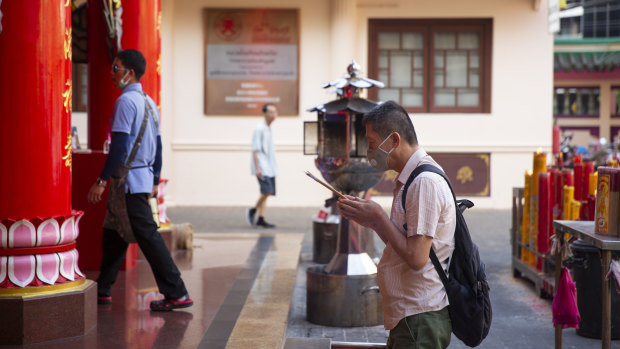 A man in a face mask prays at Kuan Yim Shrine in Bangkok, Thailand.