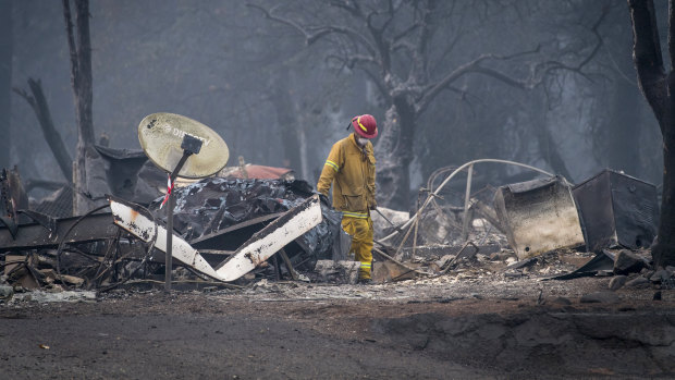 A firefighter searches a burned-out building in Paradise, California.