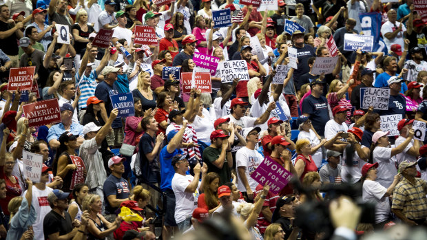 Attendees hold placards, including ones with the letter 'Q', and cheer during a rally with US President Donald Trump.