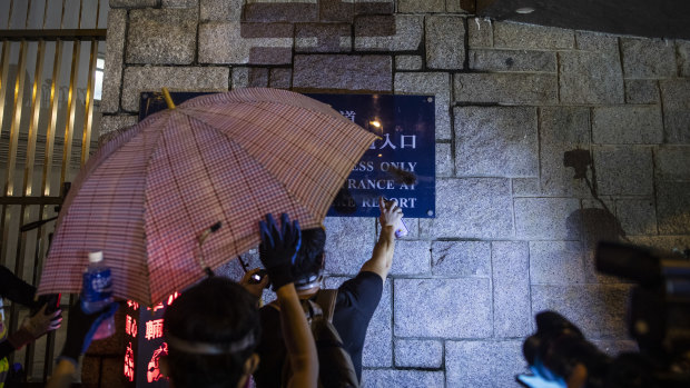 A demonstrator spray paints a sign displayed outside the Wong Tai Sin Police Station during protests in the Wong Tai Sin district of Hong Kong.