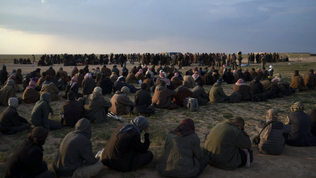 Men, foreground, women and children wait to be screened by US-backed Syrian Democratic Forces (SDF) fighters after being evacuated out of the last territory held by Islamic State militants, near Baghouz, eastern Syria, in February.