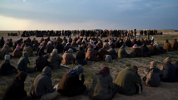 Men, foreground, women and children wait to be screened by US-backed Syrian Democratic Forces (SDF) fighters after being evacuated out of the last territory held by Islamic State militants, near Baghouz, eastern Syria, in February.