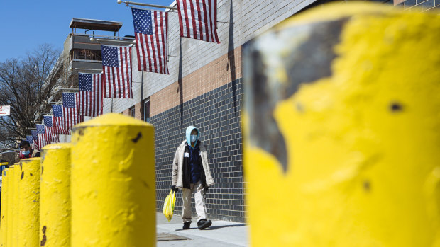 A person wearing a protective mask walks outside the Elmhurst Hospital Centre in the Queens borough of New York.