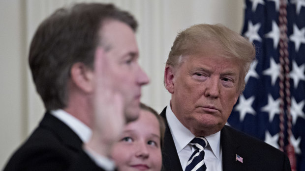 Donald Trump listens as Brett Kavanaugh takes the oath to become a Supreme Court judge.
