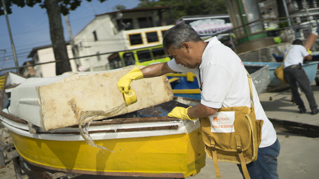 A health agent scoops water from a boat docked at the Jurujuba beach during an operation to eradicate the Aedes aegypti mosquito, in Niteroi, Brazil.
