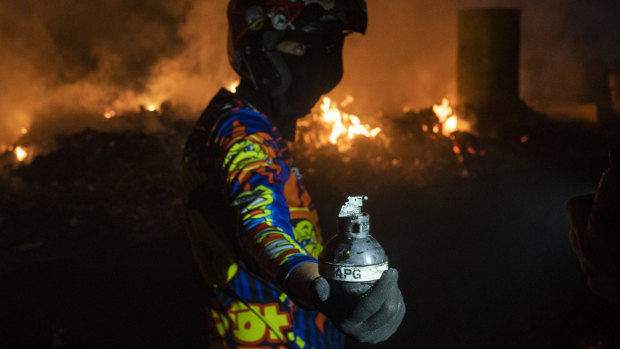 A demonstrator holds a grenade on the Francisco De Paula Santander International Bridge near the border with Venezuela in Cucuta, Colombia, on Saturday.