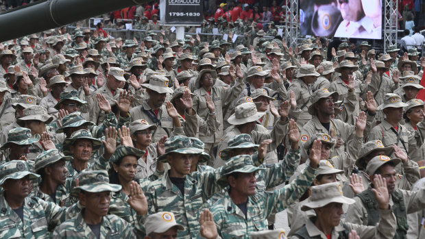 National Bolivarian Militia members raise their hands during a military parade on "National Bolivarian Militia Day" at Los Proceres in Caracas, Venezuela. 