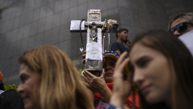 A demonstrator holds a cross during a protest on the sidelines of the visit by Michelle Bachelet, high commissioner for human rights at the UN.