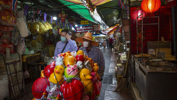 A vendor wearing a face mask wheels ceramic products on a cart in the market in Chinatown in Bangkok, Thailand.