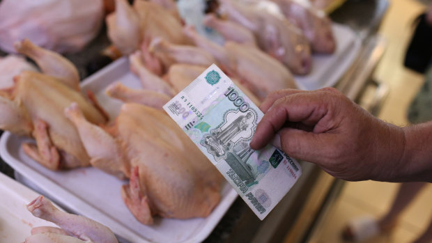 A customer hands over a 1000 ruble banknote while purchasing farm produced meat products from a trader at the Dorogomilovsky food market in Moscow, Russia, on Friday.