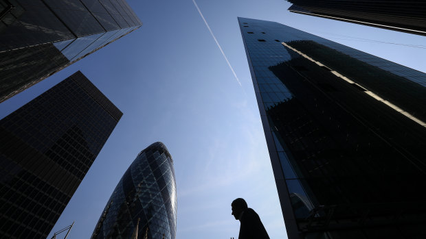 A pedestrian walks past skyscrapers including, left to right, the Leadenhall building, also known as the Cheesegrater, the Aviva Tower, and 30 St Mary Axe, also known as the Gherkin in London as May met with Brexit ministers.