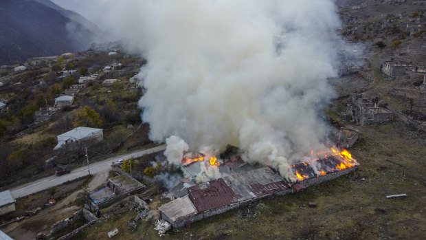 Smoke rises from a burning house in an area once occupied by Armenian forces but soon to be turned over to Azerbaijan, in Karvachar, the separatist region of Nagorno-Karabakh.