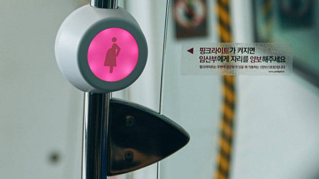A sensor next to special priority seats, blinks with pink light, signals that a pregnant passenger is approaching or standing nearby..