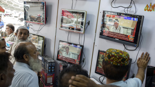 People at an electronics store watch screens showing a speech by Imran Khan on Thursday.