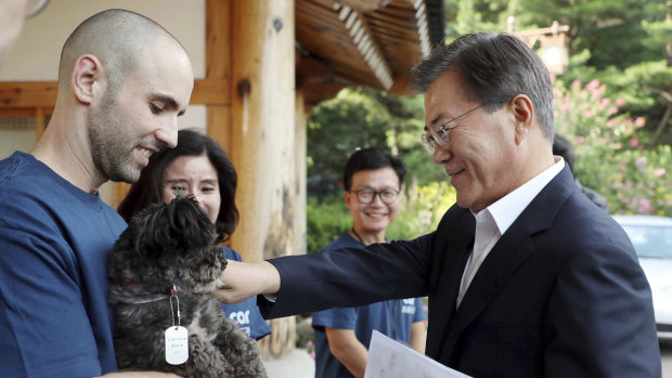 South Korean President Moon Jae-in, right, pats the dog named Tori at the presidential Blue House in Seoul.