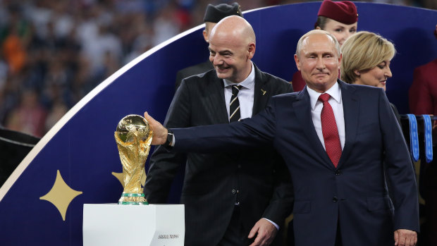 Russia's president Vladimir Putin touches the World Cup trophy as Gianni Infantino, president of FIFA, smiles during the award ceremony following the FIFA World Cup final match in Moscow, Russia, on Sunday.