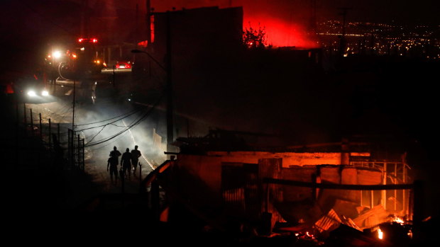 People walk away from a burning house in Valparaiso, Chile. The picturesque town has lost at least 120 homes in the Christmas Eve/Day fires.