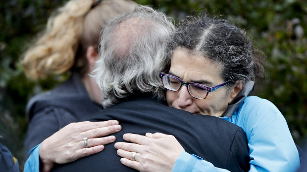 People embrace along the street in the Squirrel Hill district of Pittsburgh where a shooter opened fire during services at the Tree of Life Synagogue.