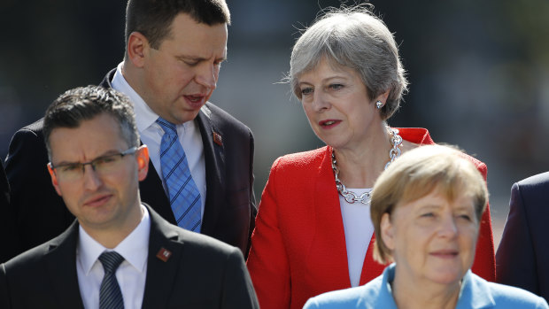 Theresa May speaks with Estonia's Prime Minister Juri Ratas during a family photo at the informal EU summit in Salzburg.