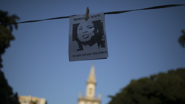 A sign with a picture of murdered councilwoman Marielle Franco with text written in Portuguese that reads "Marielle lives. I am because we are" hangs during a memorial for her and her driver Anderson Pedro Gomes, who both were killed a month ago in Rio de Janeiro.