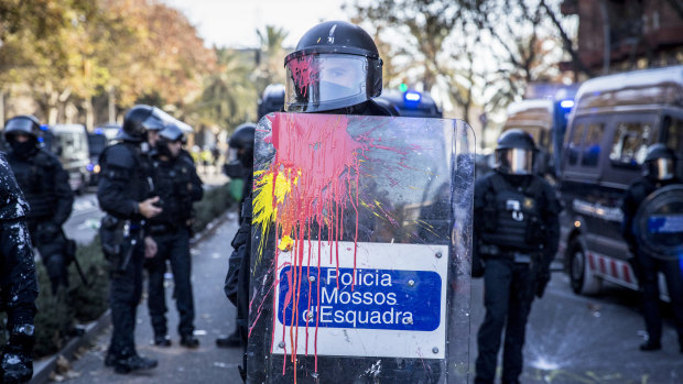 Paint splatters the riot shield and visor of a member of the Mossos d'Esquadra police force during a clash with supporters of Catalan independence on Paralelo Avenue in Barcelona, Spain.
