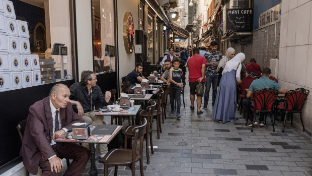 Locals sit at tables outside a tea shop on Istiklal street in Istanbul, Turkey.