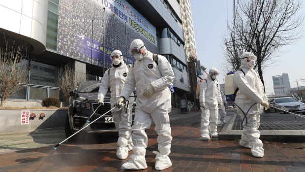 Medical workers spray disinfectant in front of a church in Daegu, South Korea.