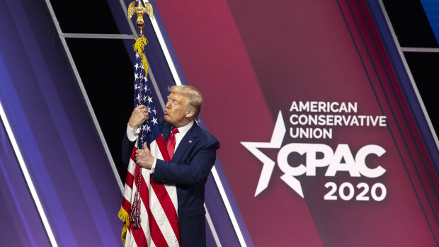 Then president Donald Trump hugs an American flag at the 2020 Conservative Political Action Conference. 