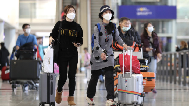 Travellers wearing face masks walk through the check-in hall at Hong Kong International Airport. 